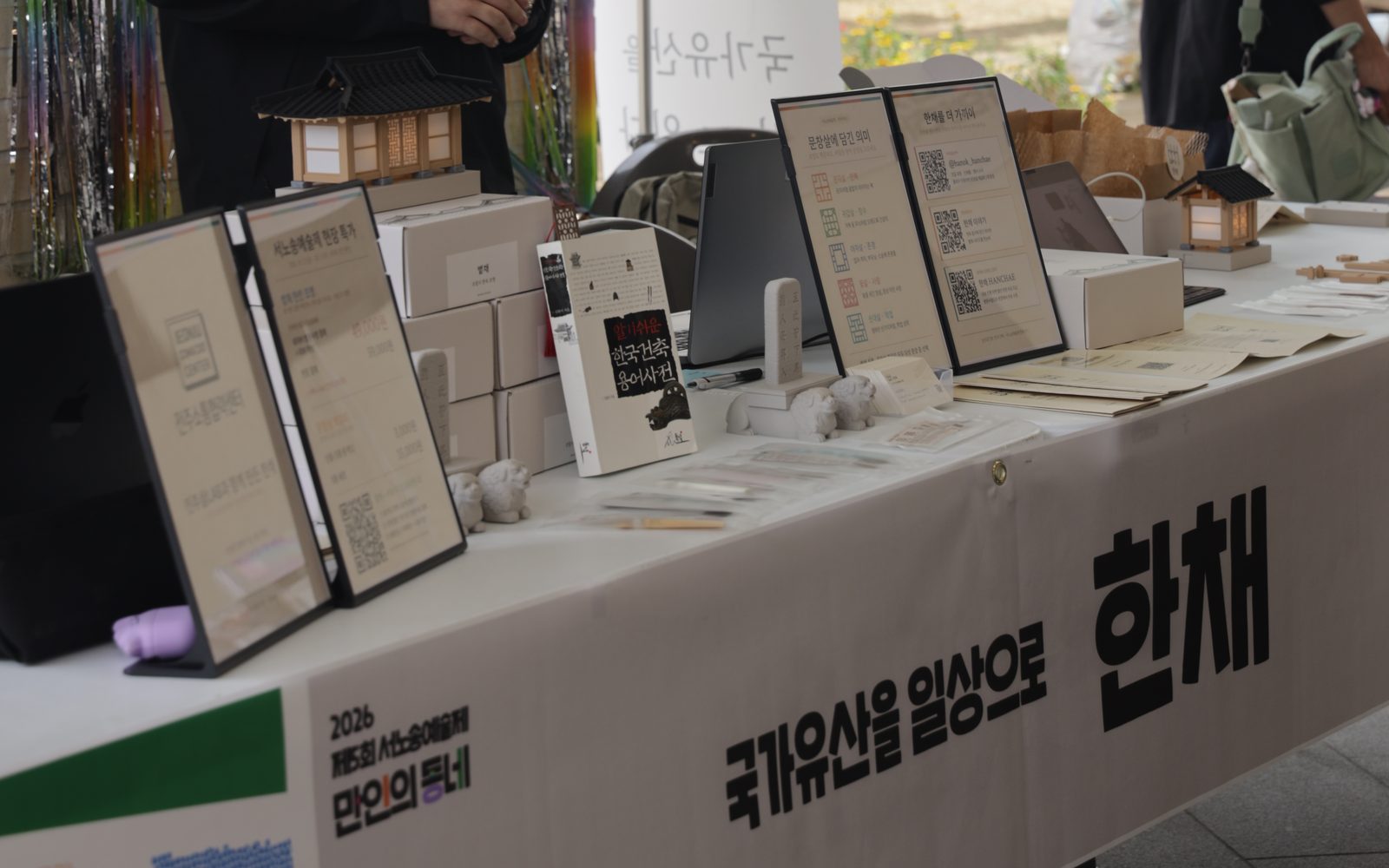 서노송예술제 한채 부스. ‘국가유산을 일상으로 한채’ 현수막을 건 테이블 위 볕채 조명과 안내판